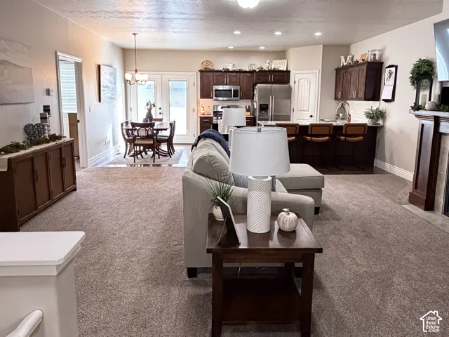 Open-concept interior featuring dark wood cabinetry, a built-in kitchen island, a fireplace with a wood mantel, and full-glass panel doors