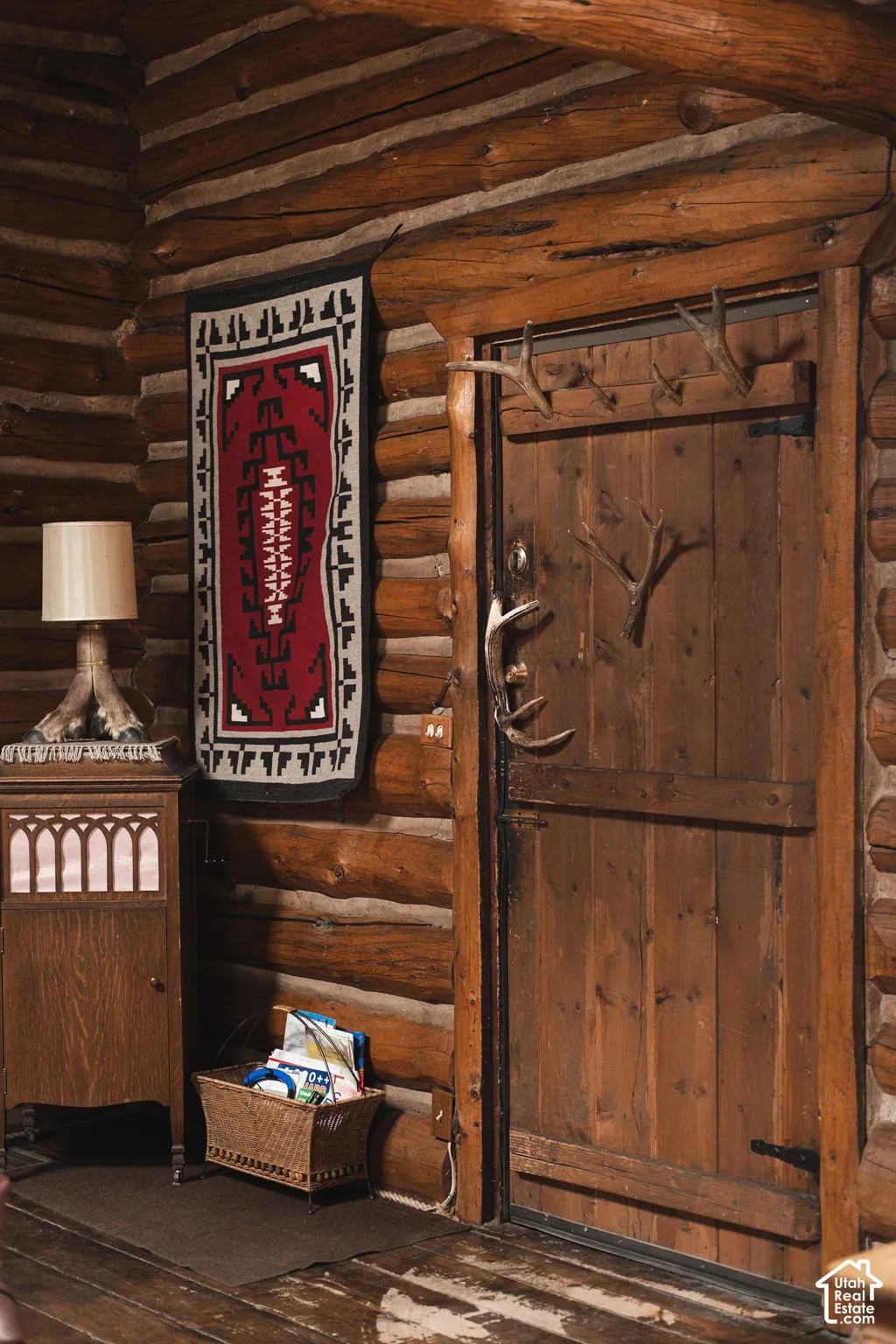 Hand-hewn log walls featuring horizontal timber construction and vertical plank door with black iron hardware