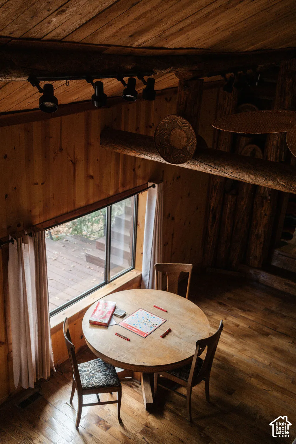 Interior featuring natural wood-plank walls and ceiling, exposed timber beam construction, hardwood flooring, and multi-light track lighting