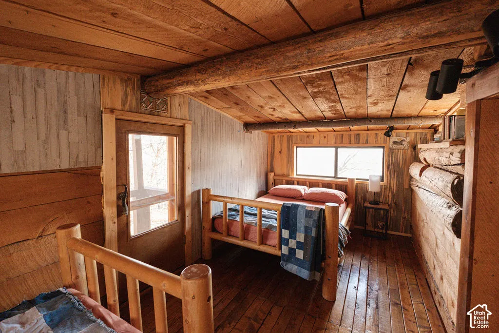 Exposed log beam ceiling, natural wood wall cladding, wood-finish flooring, and multi-pane window