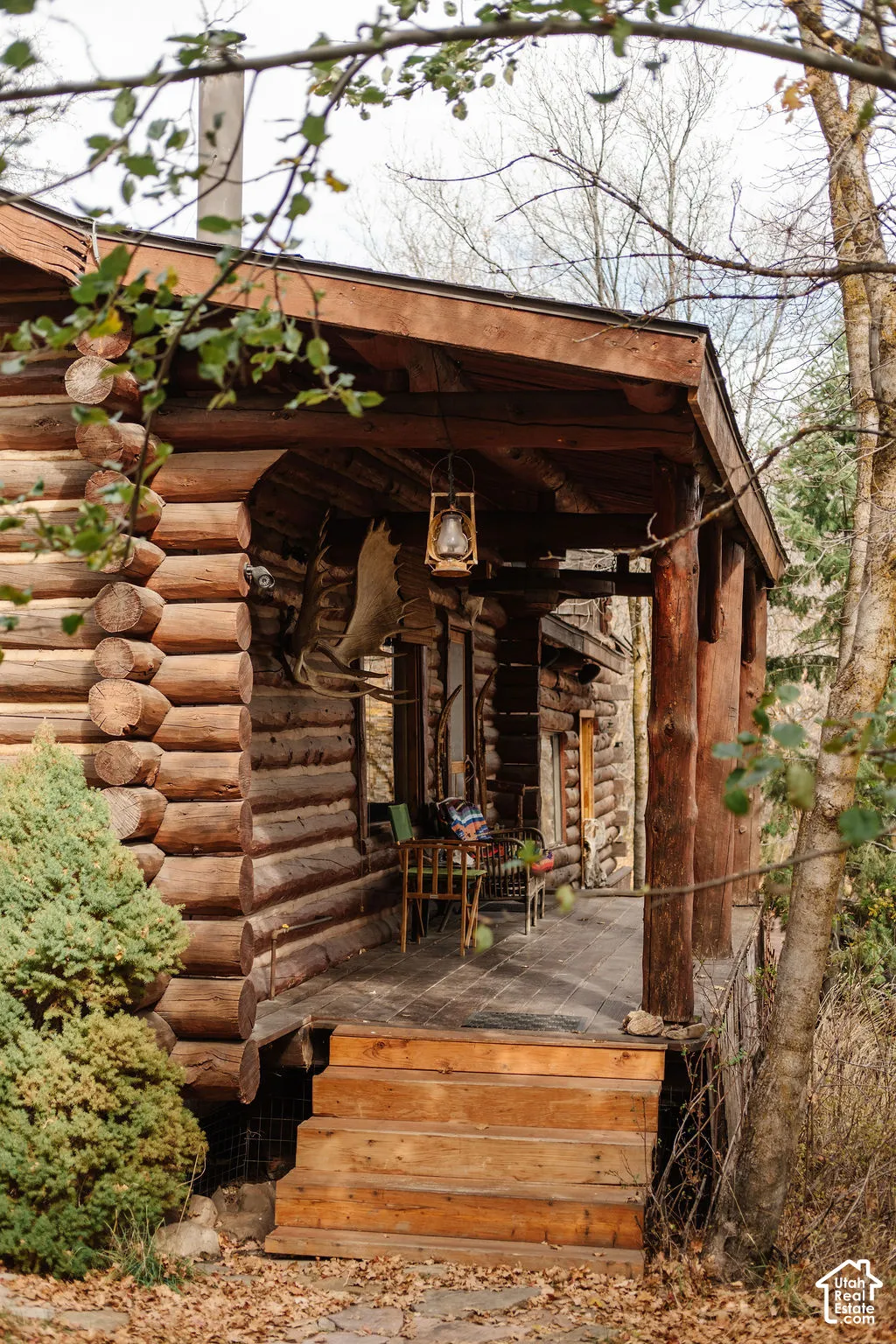 Log construction exterior featuring a covered porch, wood plank decking, and wood stairs