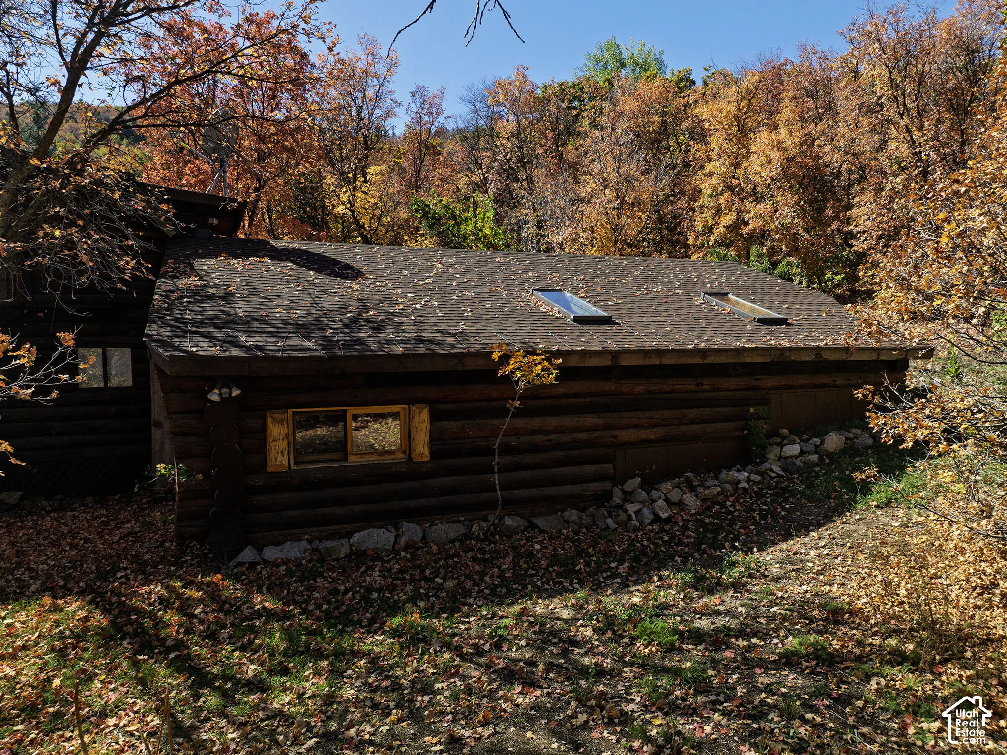Log construction exterior featuring a stone foundation, dual roof-mounted skylights, and wooden window shutters