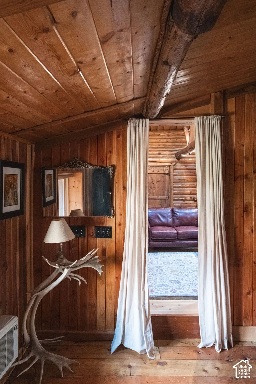 Natural wood paneled walls, ceiling beams, and plank flooring with exposed log structural elements