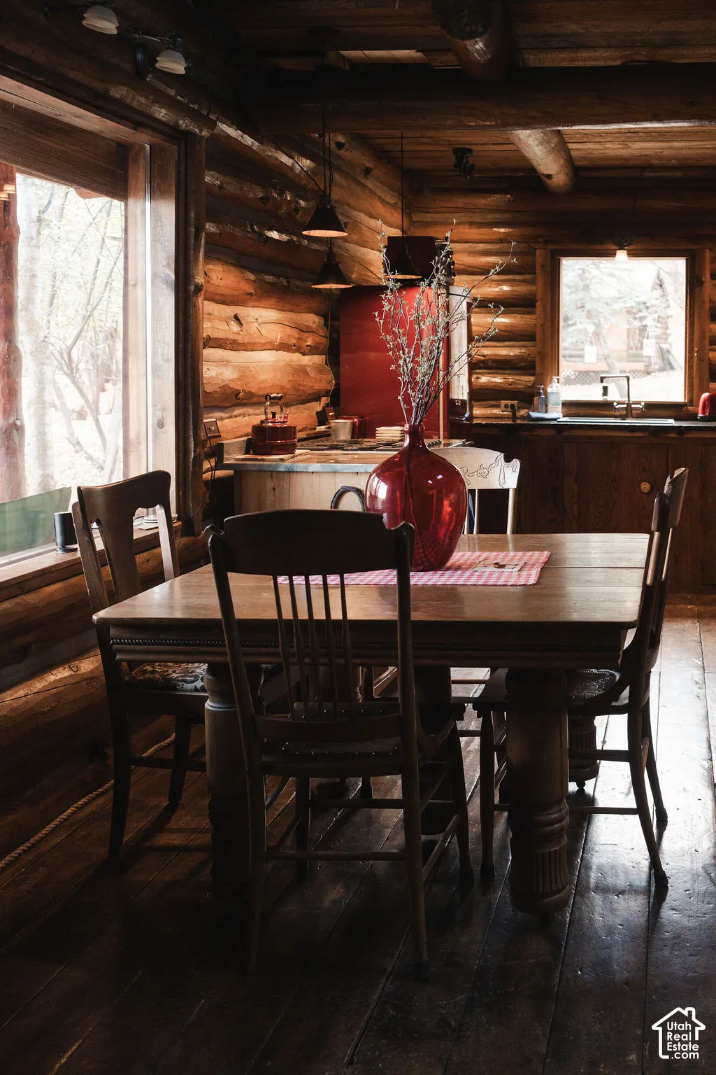 Hand-hewn log walls, exposed timber ceiling beams, wood-finish flooring, and expansive windows