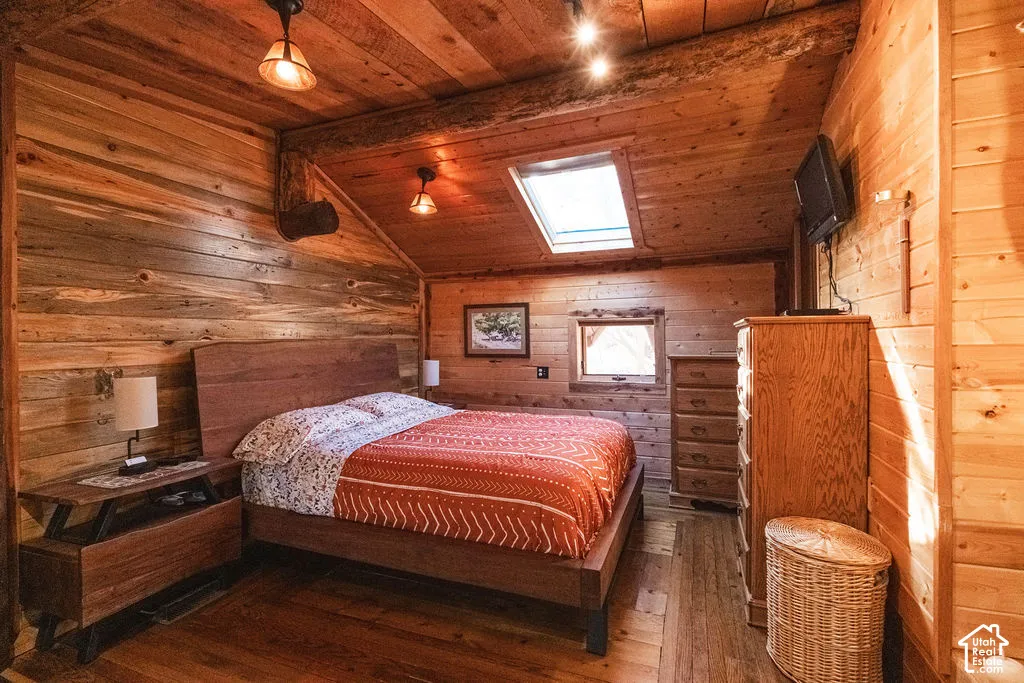 Interior space featuring natural wood wall paneling, vaulted ceiling with exposed timber beam, skylight, and recessed lighting