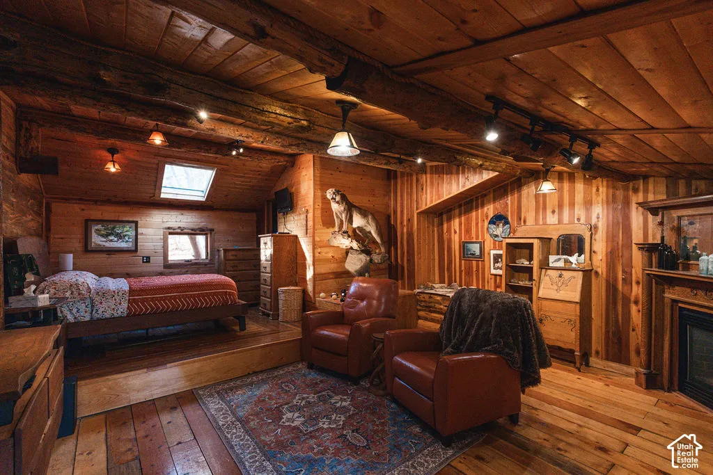 Vaulted ceilings with exposed timber beams, natural wood paneling, wood-finish flooring, a skylight, and a built-in fireplace