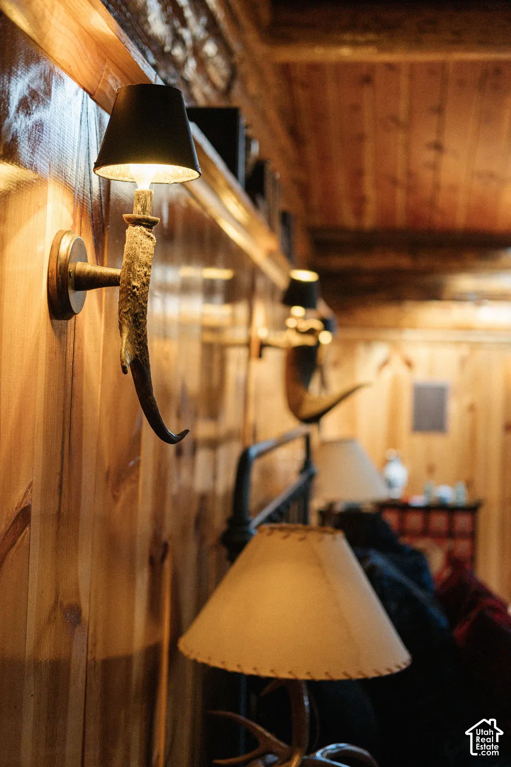Tongue-and-groove wood wall paneling and ceiling, accented by antler-style wall sconces with dark conical shades