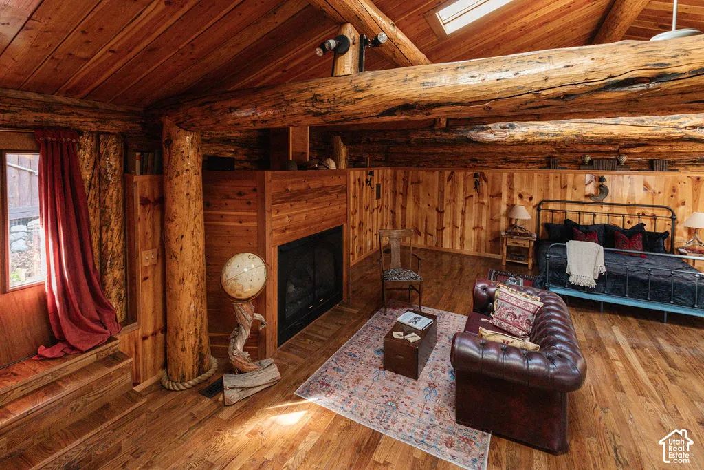 Exposed log beam construction, vaulted tongue-and-groove wood ceilings, wood-finish flooring, integrated fireplace, and skylight
