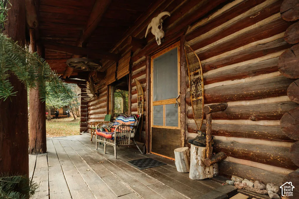 Covered porch featuring natural log wall construction, exposed timber support columns, and wood-plank decking