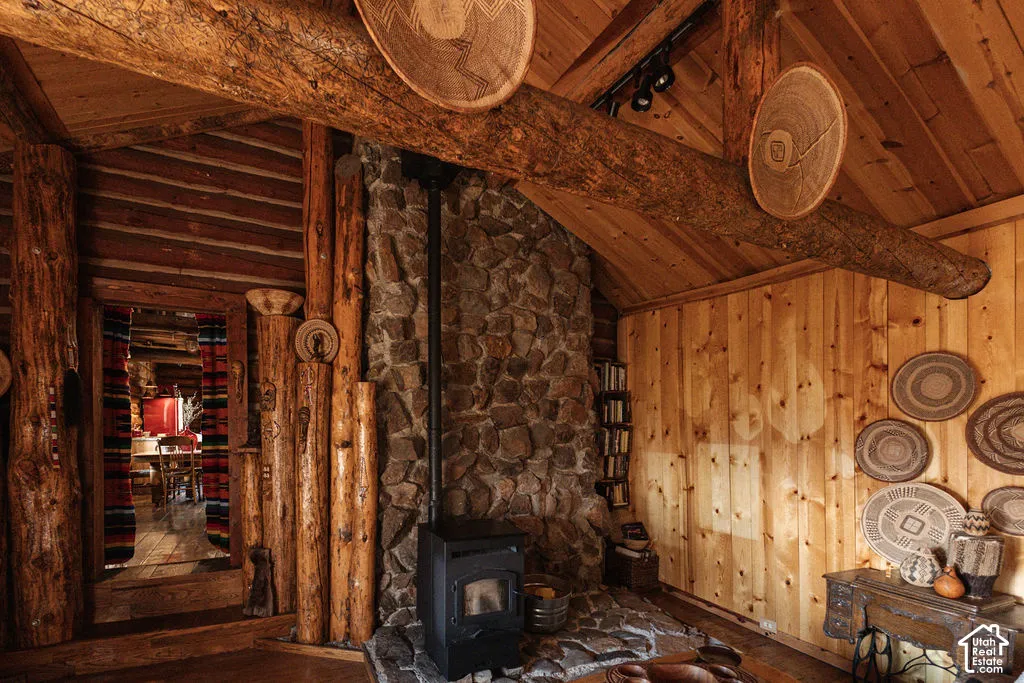 Exposed timber log beams, vertical log wall accents, natural wood-paneled walls, stone-clad fireplace hearth, and wood-finish flooring