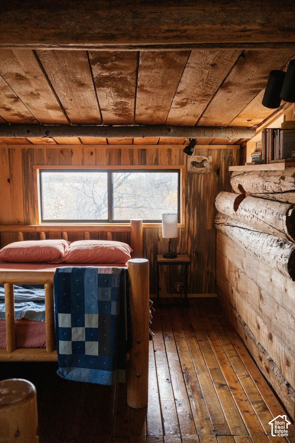 Natural wood plank walls and ceiling, exposed timber structural beams, finished wood flooring, and horizontal window pane