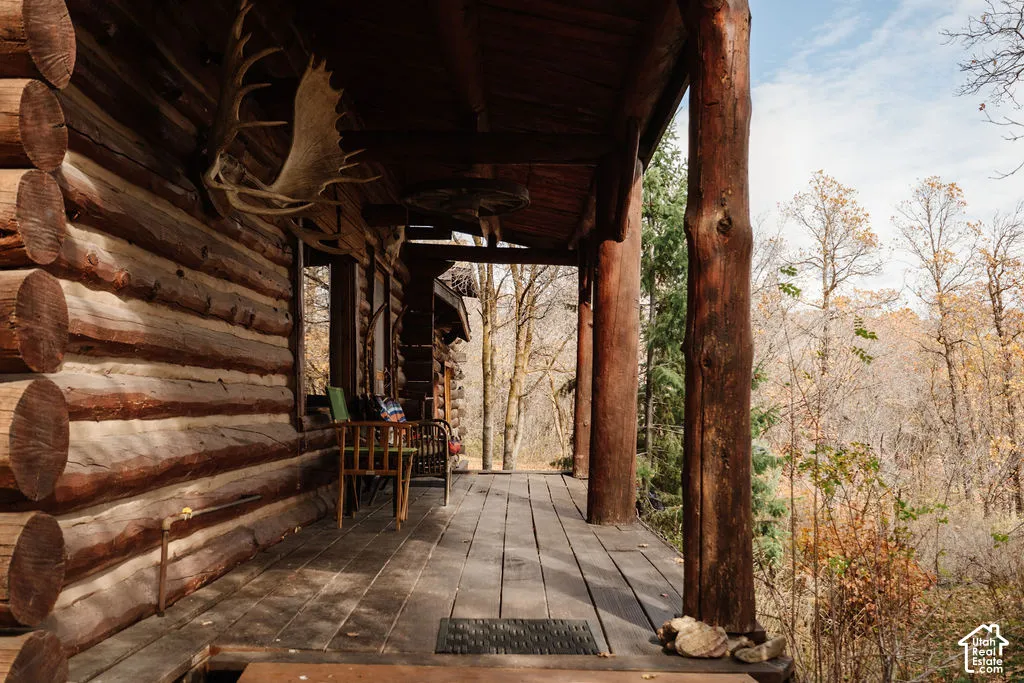 Covered exterior porch featuring handcrafted log construction, structural log pillars, and wood-plank decking