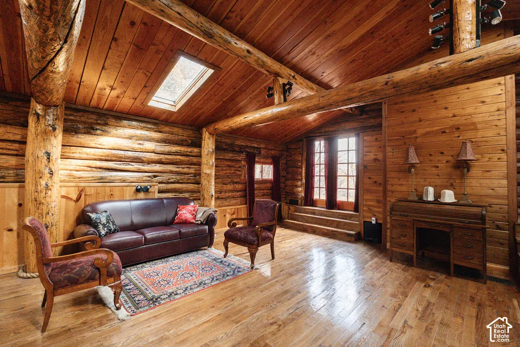 Log walls, vaulted timber-paneled ceiling, exposed log beams, wood-finish flooring, and a rectangular skylight