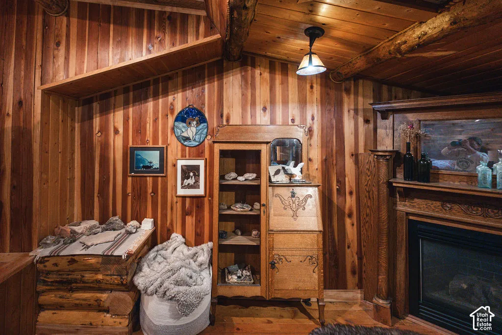 Wood-paneled interior walls, exposed log ceiling beams, fireplace with an ornate wooden mantel, and custom decorative ceiling lighting