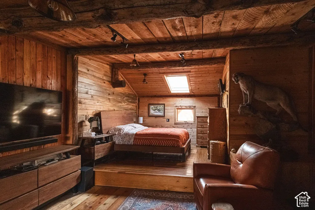 Vaulted tongue-and-groove wood plank ceiling featuring exposed timber beams, skylight, recessed track lighting, and raised platform flooring