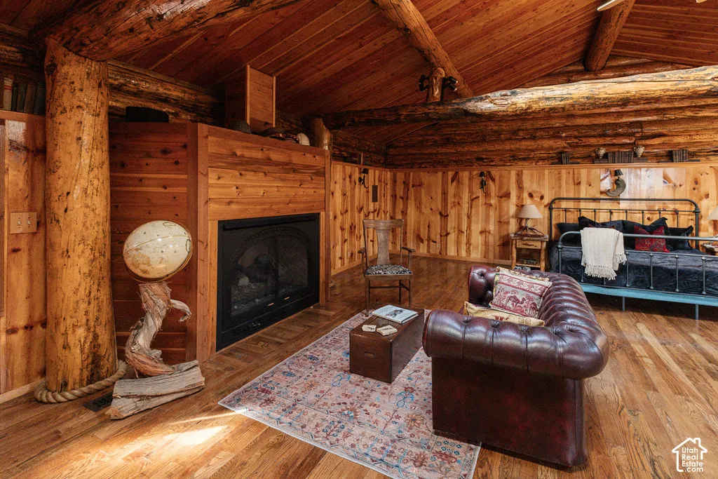Exposed log wall construction, vaulted wood-paneled ceiling, integrated wood fireplace surround, and wood-finish flooring