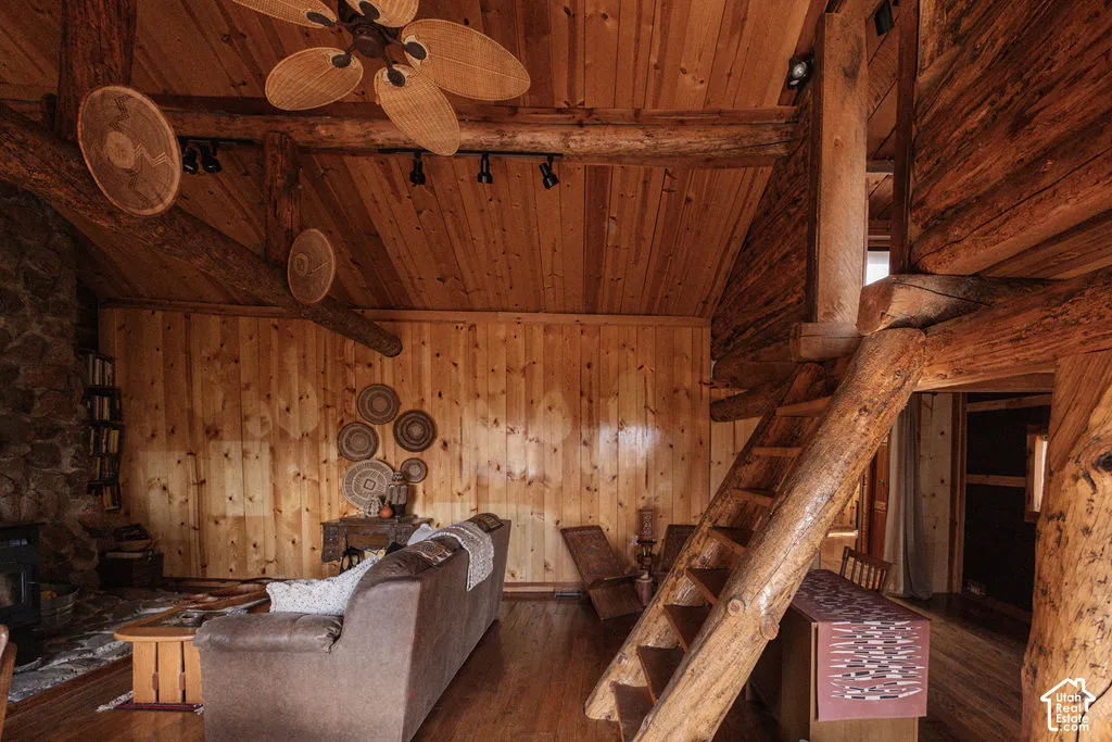 Vaulted wood-paneled ceiling with exposed log beams, natural stone fireplace, and custom log-style staircase