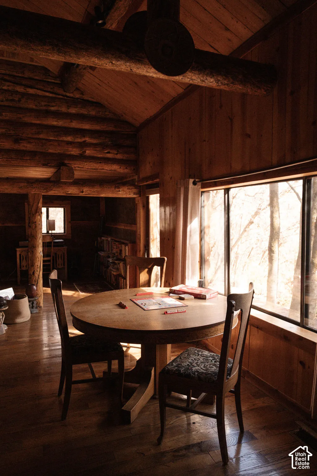Log interior featuring exposed timber beams, vertical wood paneling, wood-finish flooring, and expansive picture windows