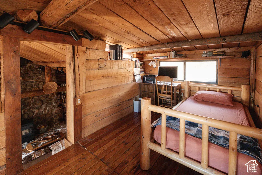 Exposed log walls, wood-plank ceiling, natural wood-finish flooring, and built-in shelving
