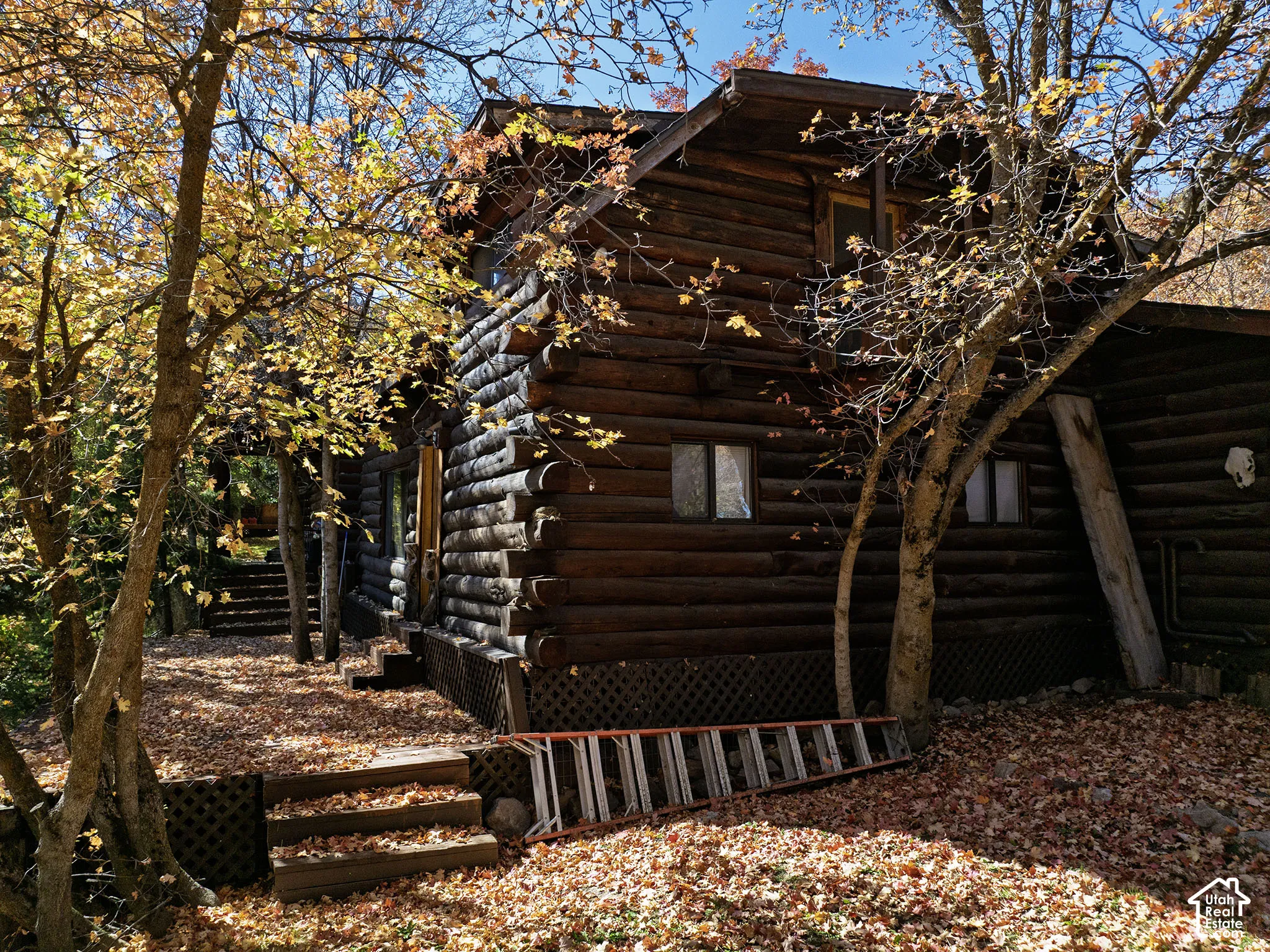 Log exterior featuring interlocking notched timber construction, multi-level wood decking, and built-in lattice skirting
