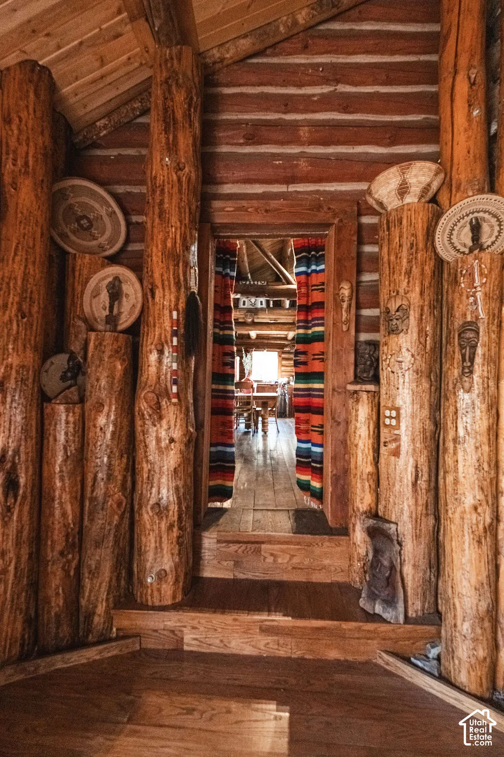 Exposed log wall construction featuring vertical timber support pillars and wood-plank flooring