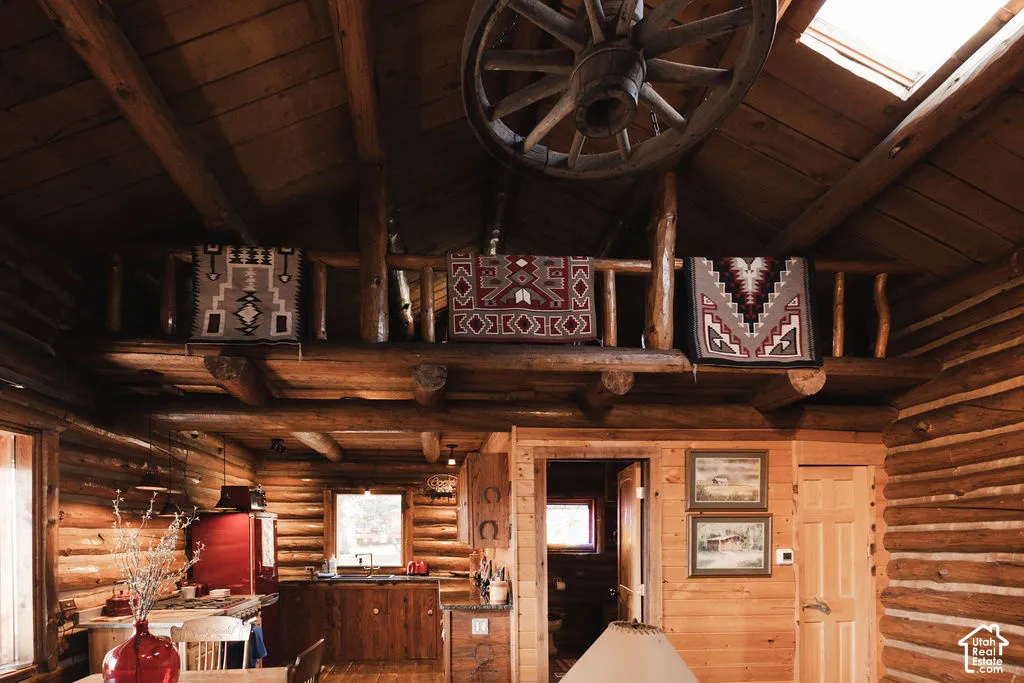 Exposed log walls, vaulted wood-plank ceiling with skylight, and timber loft with rustic railing
