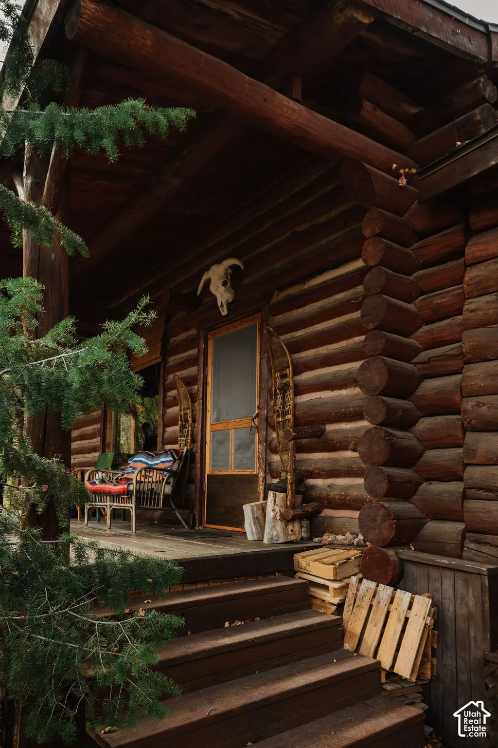 Log-style exterior featuring stacked timber walls, a covered porch, and wood-tread stairs