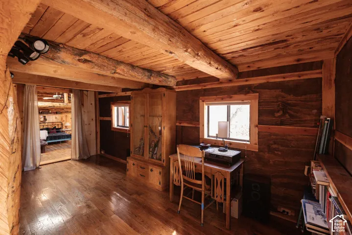 Rustic interior featuring exposed structural log beams, wood-plank ceilings, and wood-finish flooring