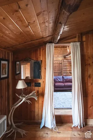 Natural wood paneled walls, ceiling beams, and plank flooring with exposed log structural elements