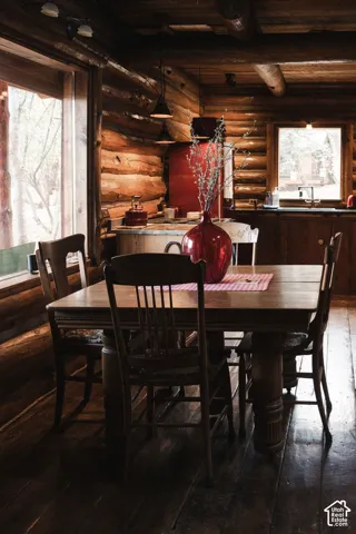 Hand-hewn log walls, exposed timber ceiling beams, wood-finish flooring, and expansive windows