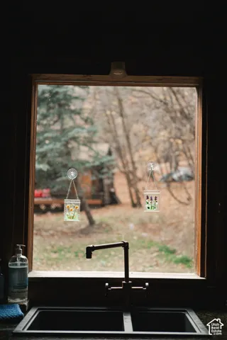 Large square-pane window featuring a wooden frame, paired with a dark-toned dual-basin undermount sink and a matte-finish gooseneck faucet
