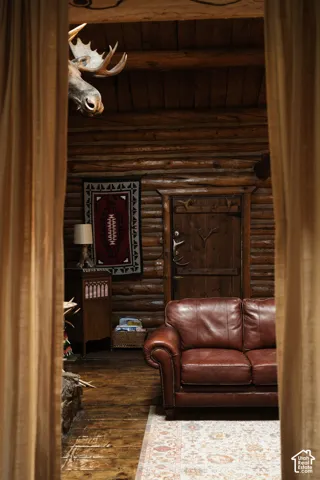 Rustic log interior featuring exposed timber wall construction, solid wood plank flooring, and a handcrafted wooden door with integrated antler detailing