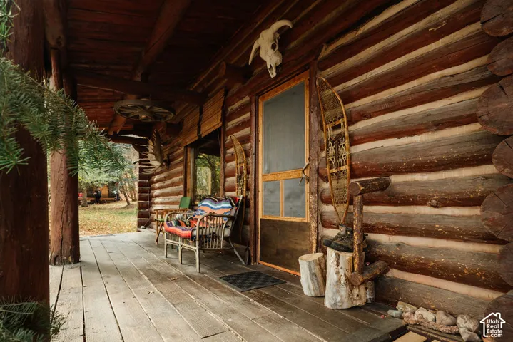 Covered porch featuring natural log wall construction, exposed timber support columns, and wood-plank decking