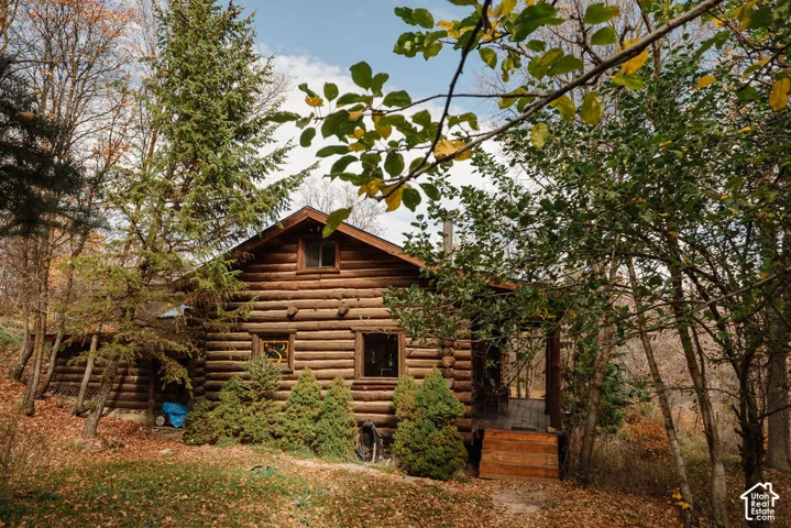 Log cabin exterior featuring horizontal log construction, a gable roofline, and an integrated covered porch with wooden steps