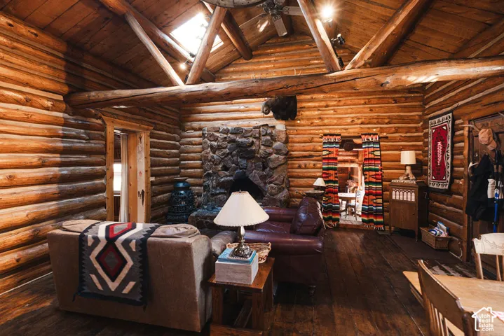 Exposed log walls, vaulted timber ceiling, stone fireplace, and integrated skylight