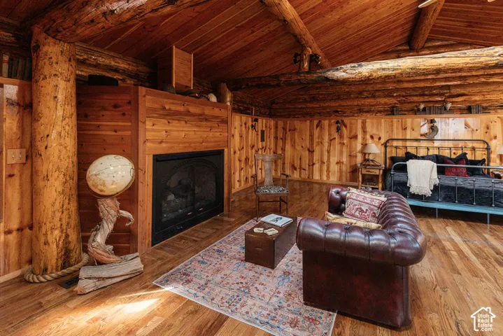 Exposed log wall construction, vaulted wood-paneled ceiling, integrated wood fireplace surround, and wood-finish flooring
