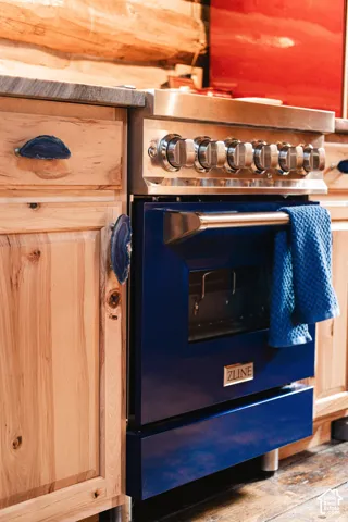 Custom cabinetry with knotty wood grain and stone-style cabinet pulls, professional-grade blue range with stainless steel control knobs, and polished stone-surface countertop