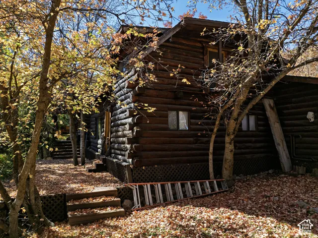 Log exterior featuring interlocking notched timber construction, multi-level wood decking, and built-in lattice skirting