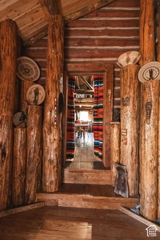 Exposed log wall construction featuring vertical timber support pillars and wood-plank flooring