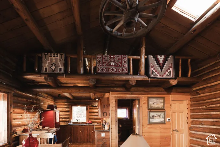 Exposed log walls, vaulted wood-plank ceiling with skylight, and timber loft with rustic railing
