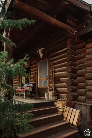 Log-style exterior featuring stacked timber walls, a covered porch, and wood-tread stairs