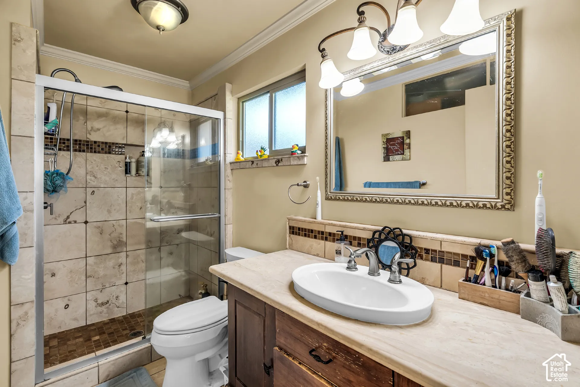 Bathroom featuring a walk-in shower with tile surround, vanity with an integrated basin, decorative mirror with a metallic frame, and overhead vanity lighting