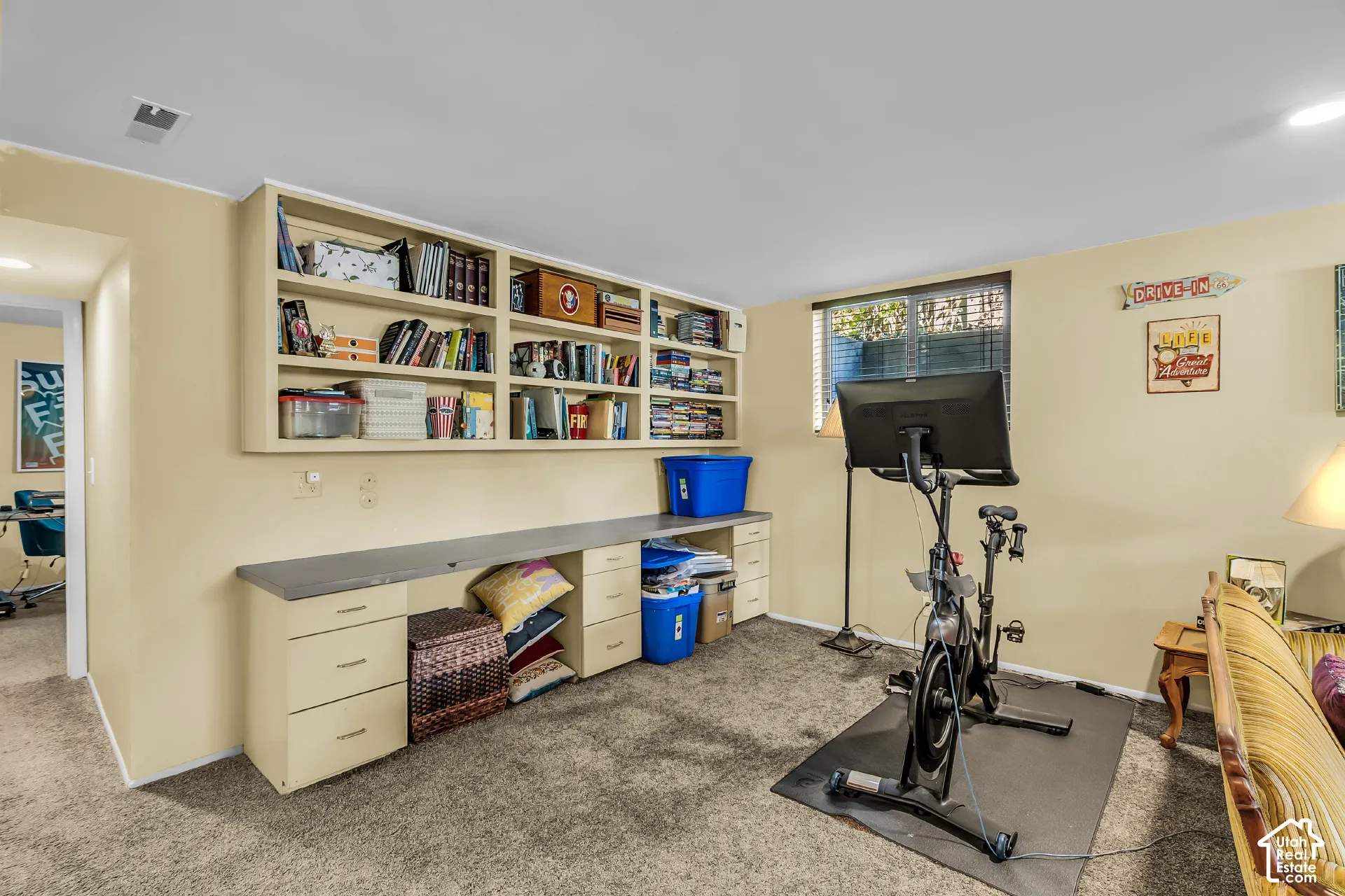 Built-in floor-to-ceiling shelving, extensive drawer storage, integrated desk surface, and window with garden-level window well