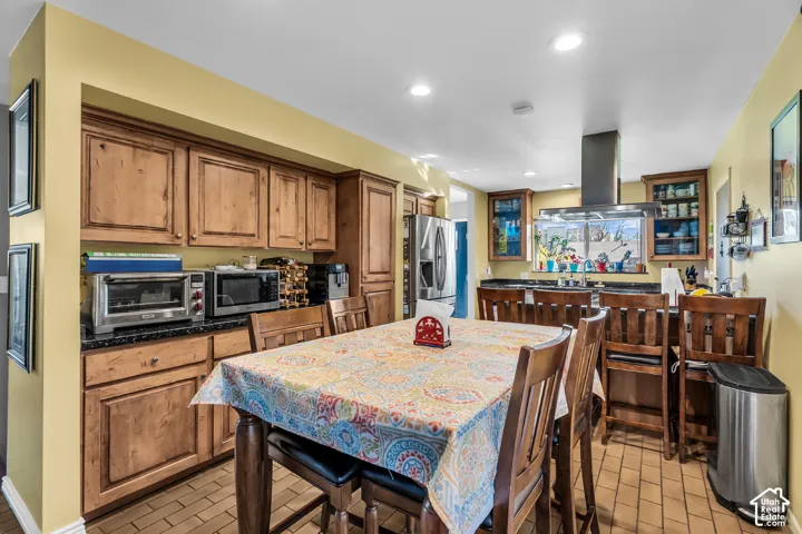 Kitchen featuring wood cabinetry, stone countertops, stainless steel appliances, a stainless steel range hood, and tile flooring