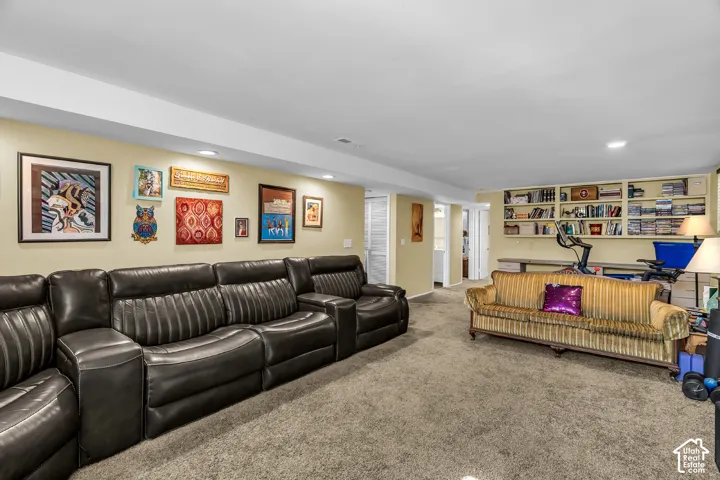 Open-concept interior featuring recessed lighting, wall-to-wall carpeting, and custom built-in cabinetry with integrated shelving and desk space