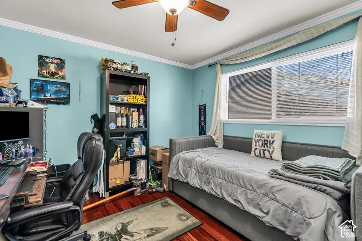 Room featuring wood-finish flooring, crown molding, horizontal window blinds, and a ceiling fan