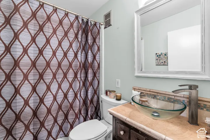 Bathroom vanity featuring a natural stone countertop, glass vessel sink, dark wood-finish cabinetry, and a wall-mounted framed mirror