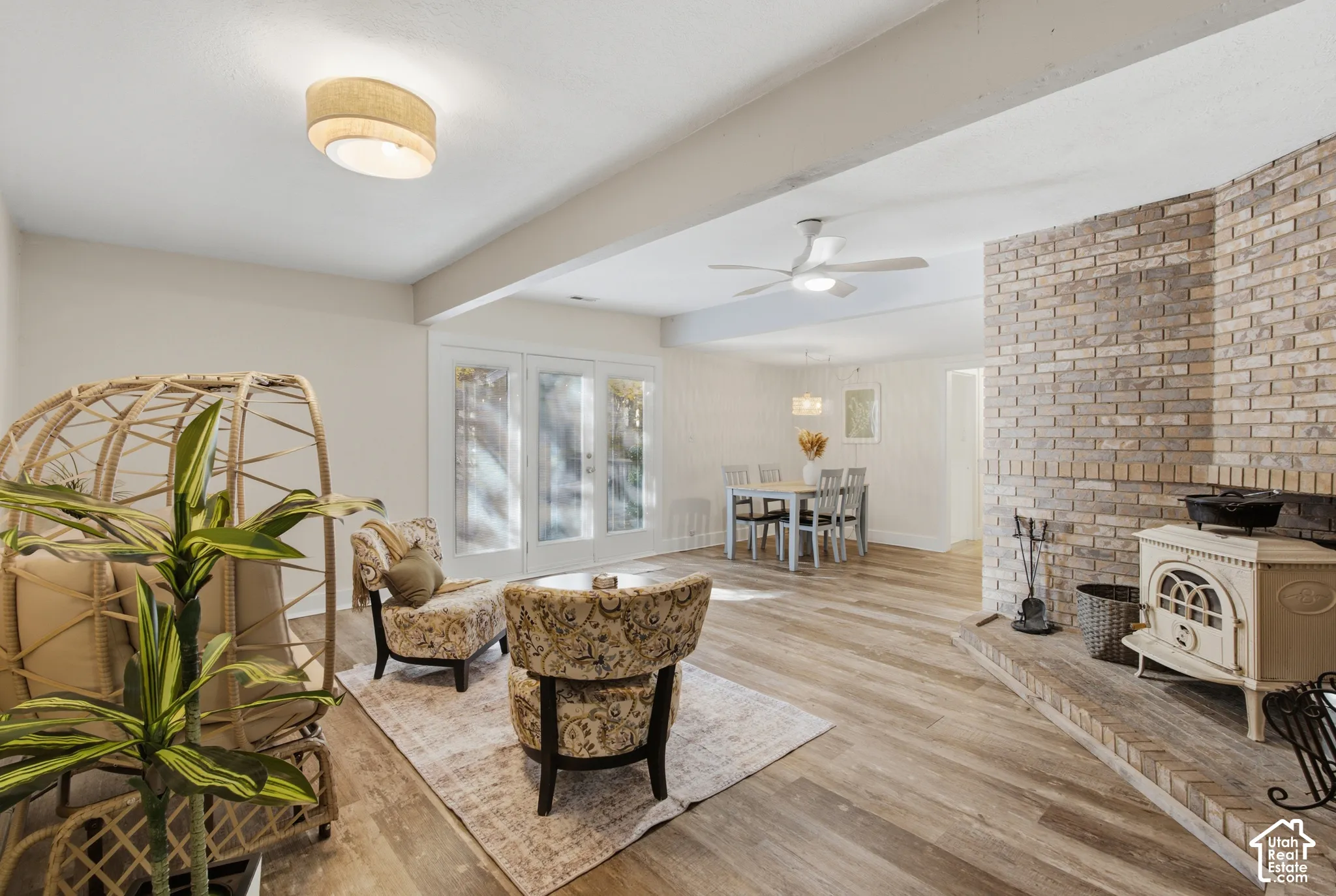Second living room area with lighting, a white ceiling fan, wood burning fireplace and glass-paneled exterior doors going to the patio