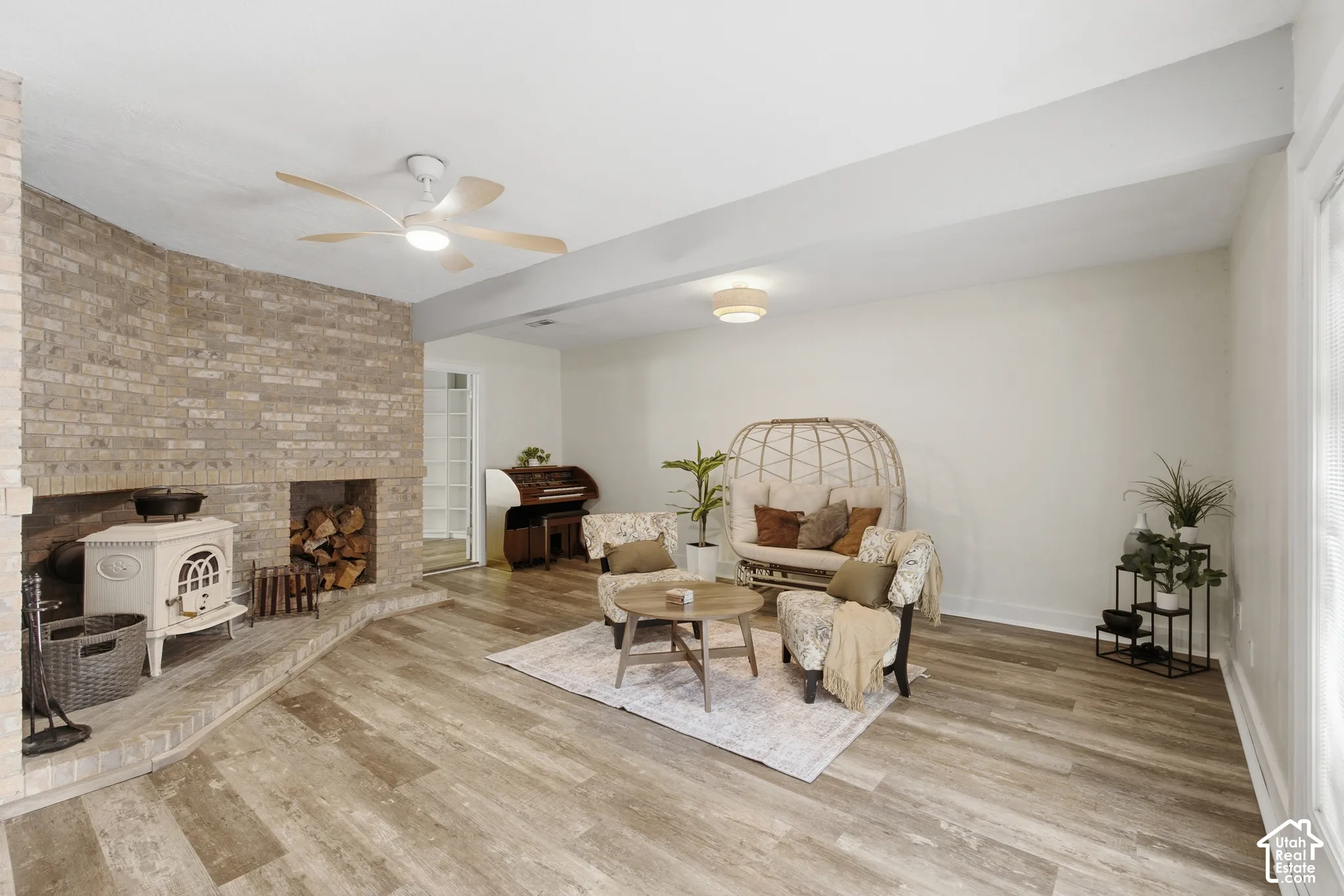 Second living room featuring wood-finish flooring, a floor-to-ceiling brick fireplace with wood burning stove