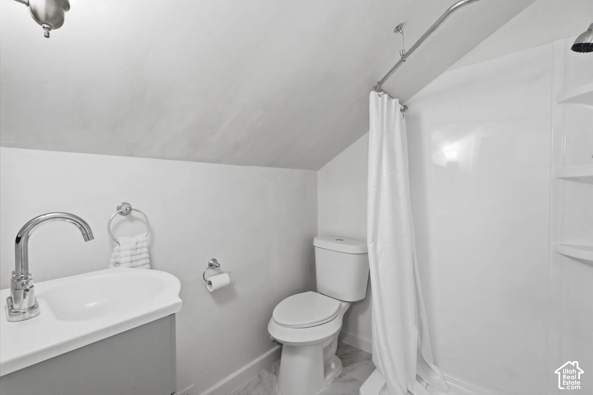 Bathroom featuring a  sink and chrome faucet, a standard-height toilet, and a shower enclosure